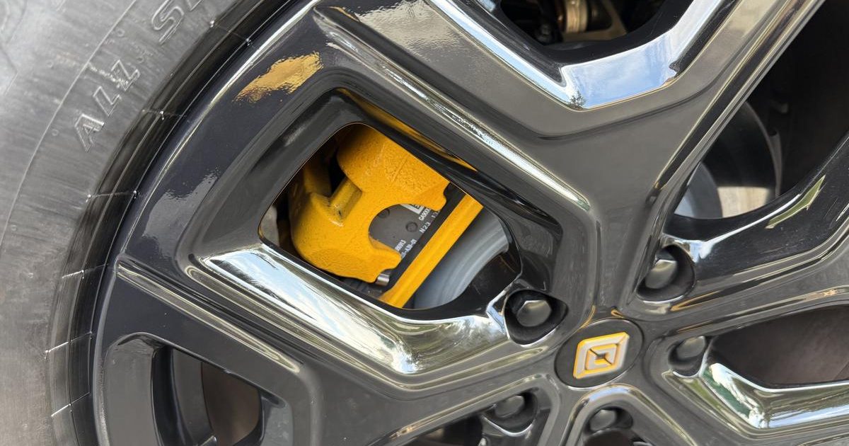 Gloss black and chrome alloy wheel with a yellow brake caliper after refinishing